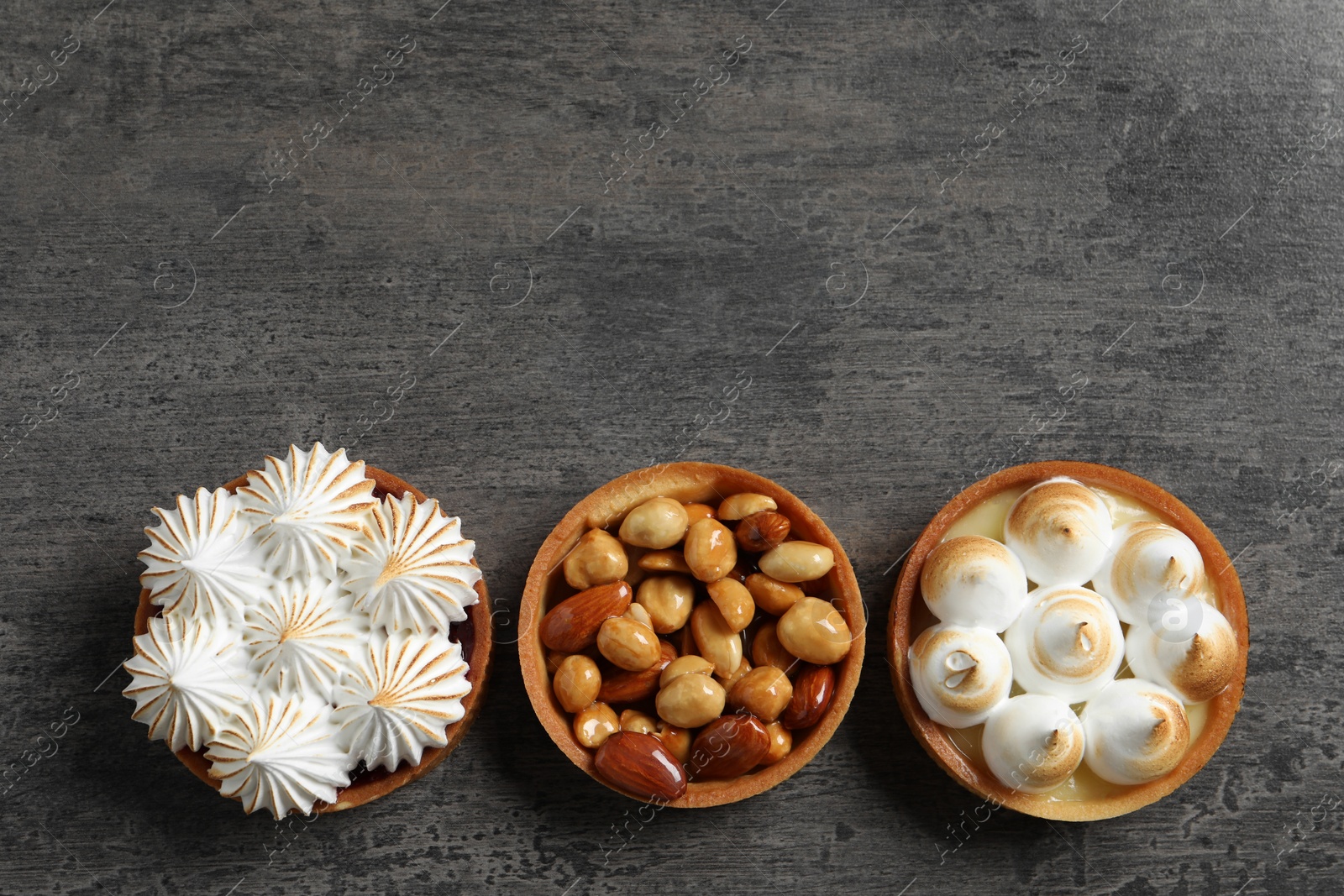 Photo of Different tartlets on dark grey table, flat lay with space for text. Tasty dessert