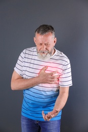 Mature man having heart attack on gray background