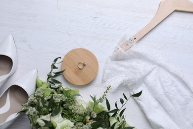 Beautiful wedding dress, shoes, engagement ring and flowers on white wooden background, flat lay