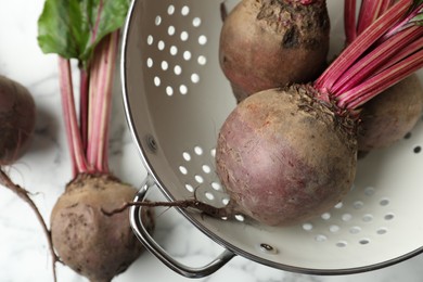 Raw ripe beets in colander on table, closeup