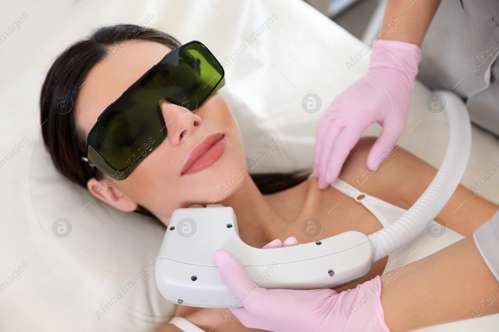 Photo of Young woman undergoing laser epilation procedure in beauty salon