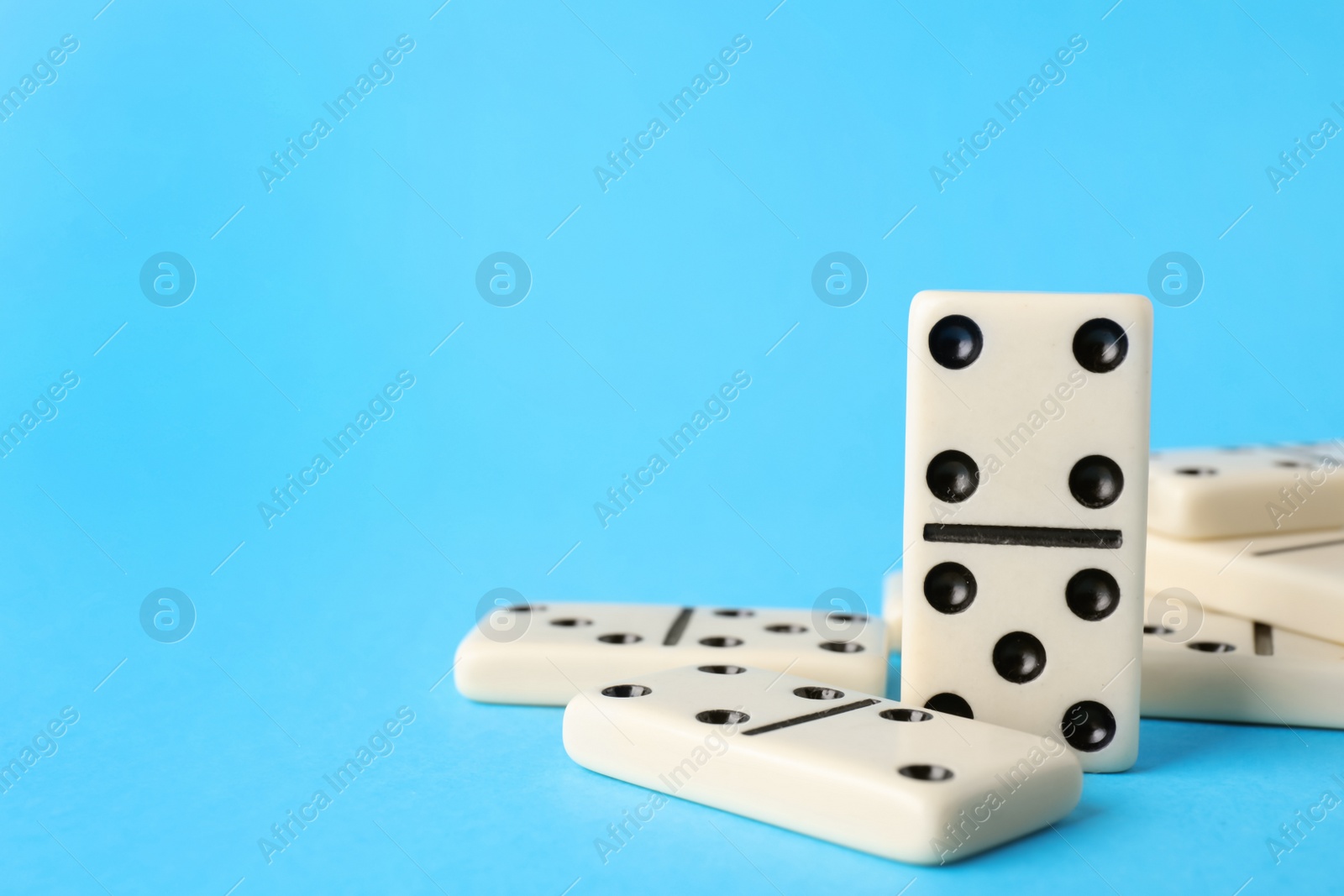 Photo of White domino tiles on turquoise background. Space for text