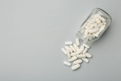 Vitamin pills and bottle on grey background, top view. Space for text