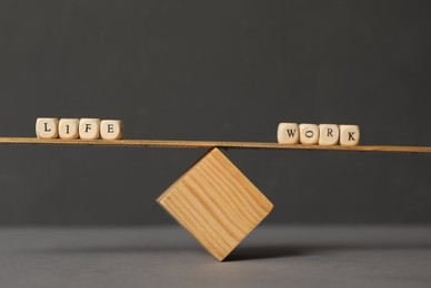 Photo of Wooden scale with words Life, Work made of cubes on grey background. Balance concept