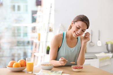 Photo of Young woman in fitness clothes having healthy breakfast at home