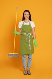 Photo of Beautiful young woman with broom on yellow background