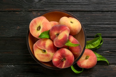 Photo of Fresh ripe donut peaches on black wooden table, flat lay