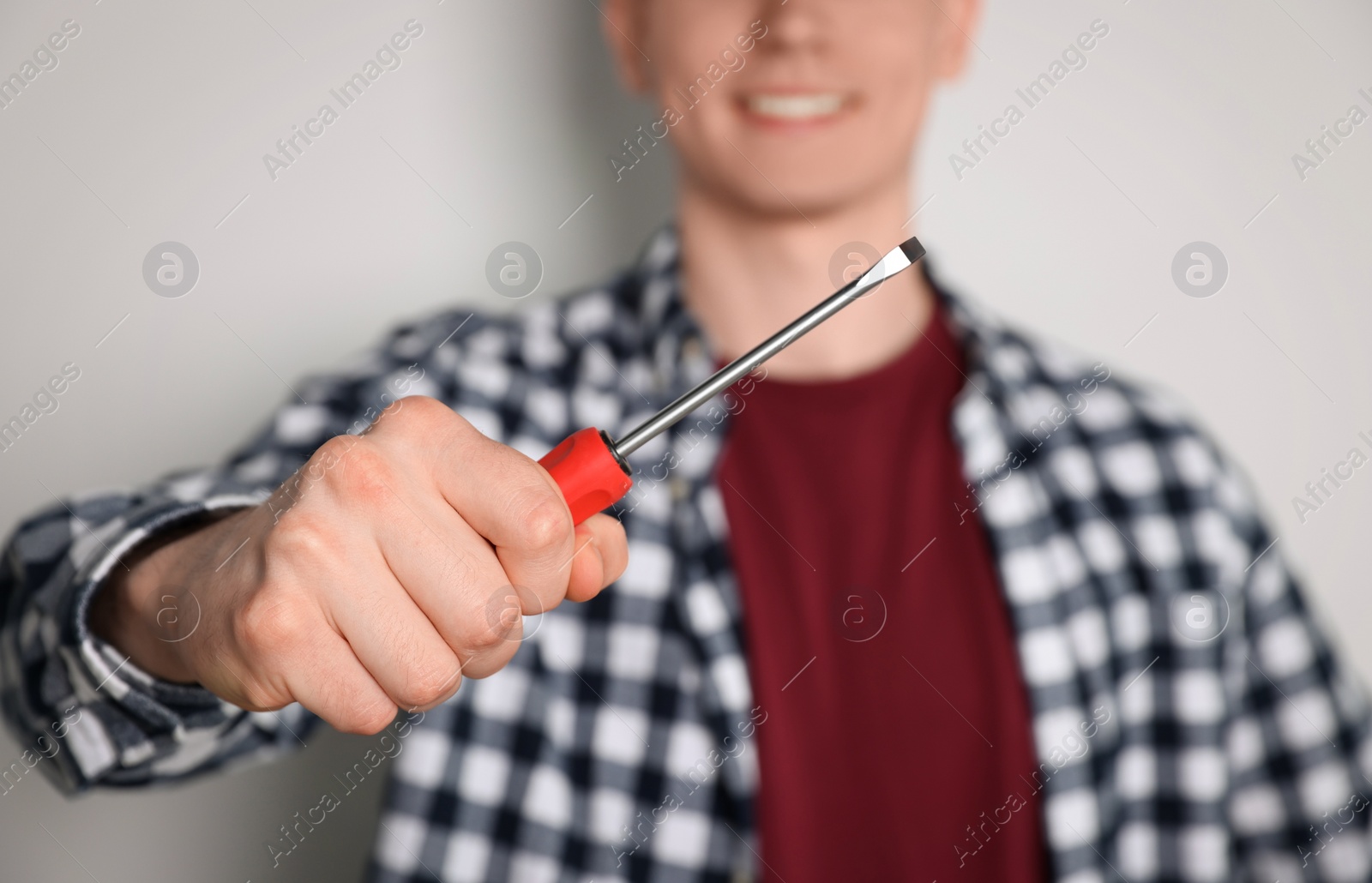 Photo of Handyman with screwdriver against light background, focus on hand