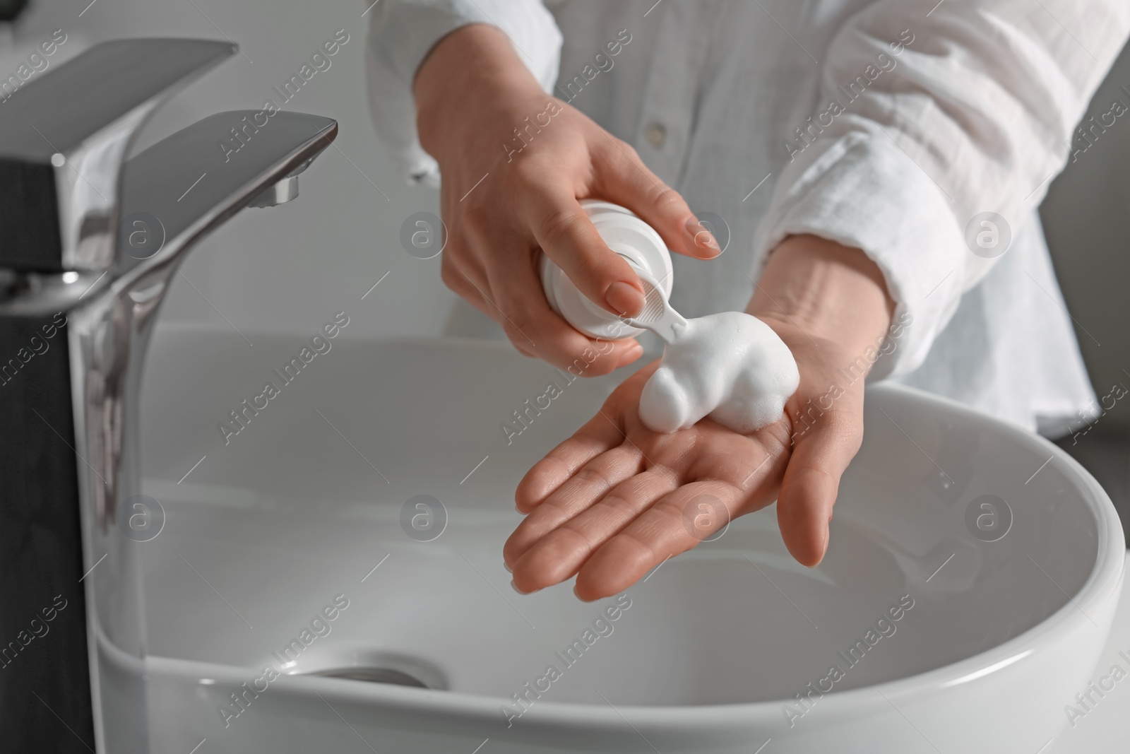 Photo of Woman washing hands with cleansing foam near sink in bathroom, closeup