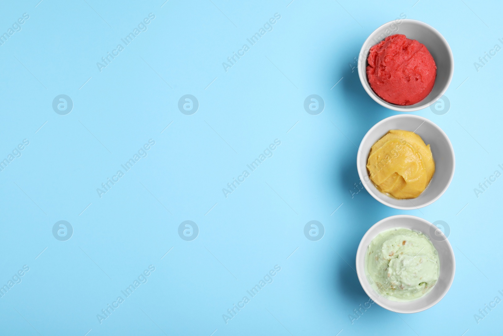 Photo of Different delicious ice creams on light blue background, flat lay. Space for text