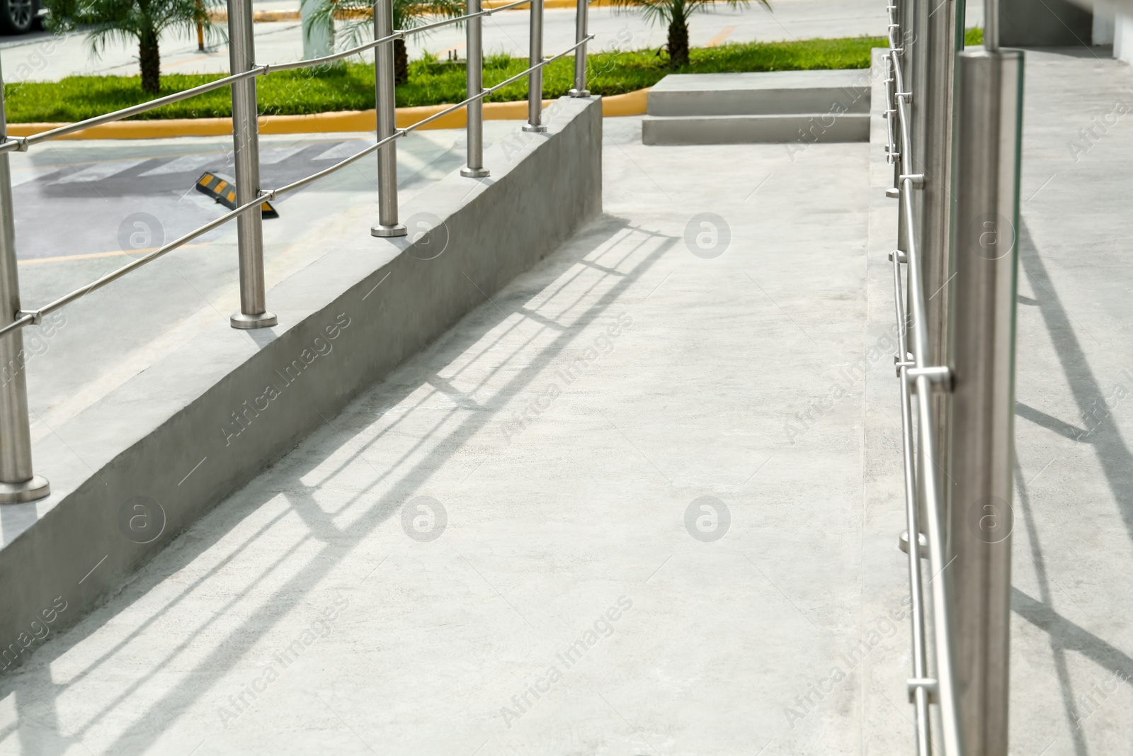 Photo of Concrete ramp with shiny metal railings outdoors