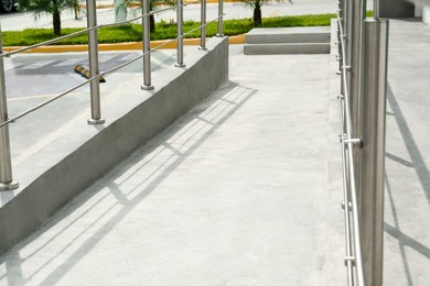 Concrete ramp with shiny metal railings outdoors