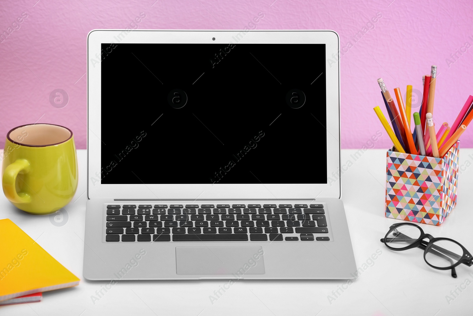 Photo of Modern laptop on table against color wall. Mock up with space for text