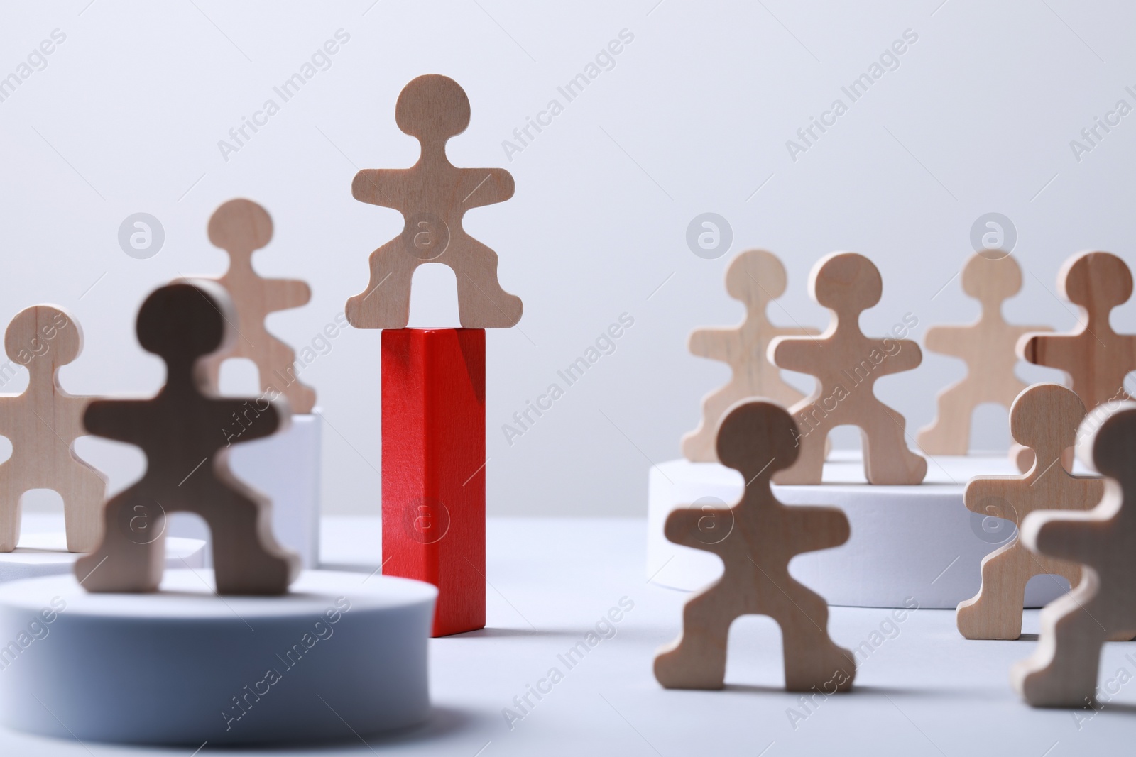 Photo of Recruitment and hiring concept. Human wooden figure on red stand among others on white table