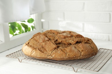 Photo of Freshly baked sourdough bread on white wooden table indoors