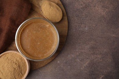 Photo of Soluble fiber with water in glass, powder and spoon on brown table, top view. Space for text