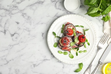 Baked eggplant with tomatoes, cheese and basil served on white marble table, flat lay. Space for text