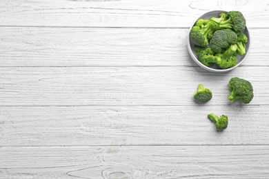 Flat lay composition of fresh green broccoli on white wooden table, space for text