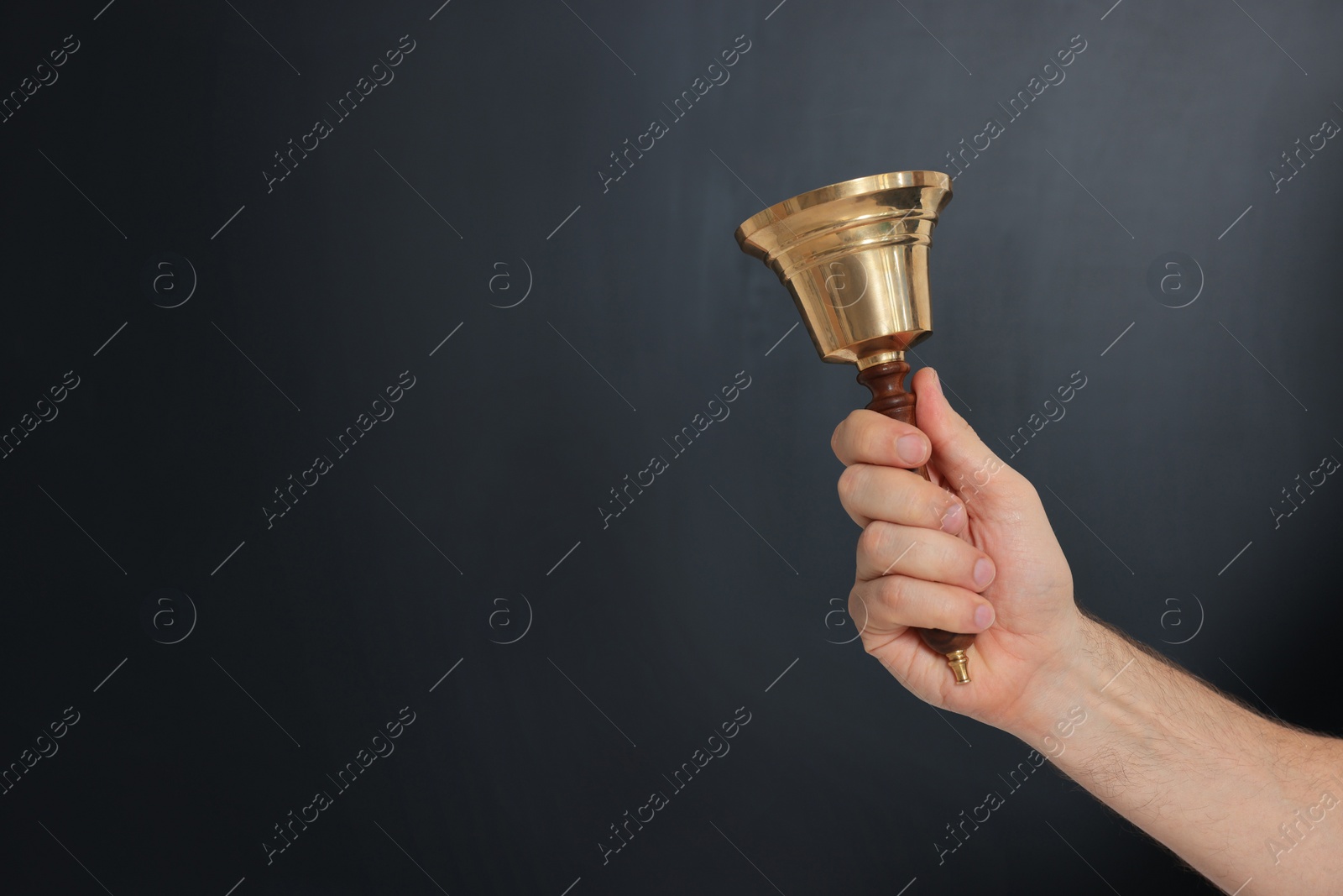 Photo of Teacher with school bell near black chalkboard, closeup. Space for text