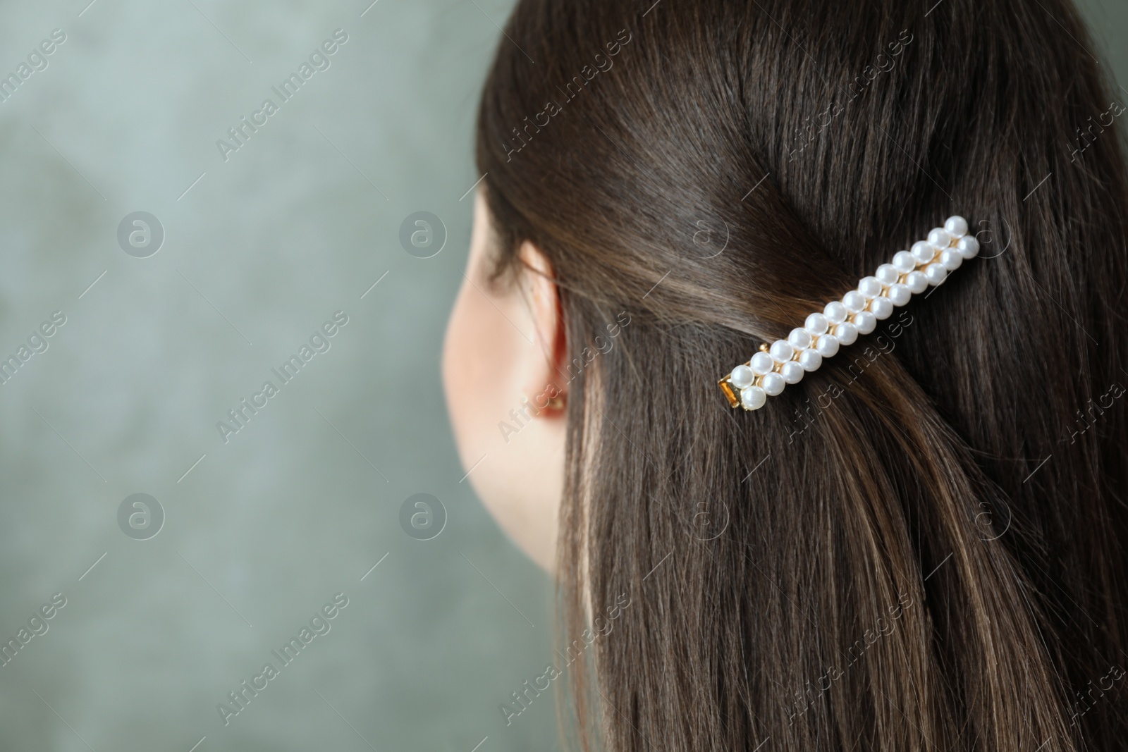 Photo of Young woman with beautiful hair clip on grey background, closeup