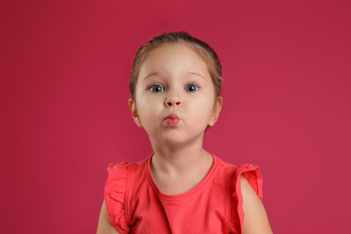 Portrait of cute little girl on pink background