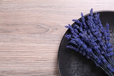 Photo of Bouquet of beautiful preserved lavender flowers and plate on wooden table, top view. Space for text