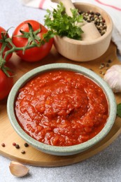 Photo of Homemade tomato sauce in bowl and fresh ingredients on light grey table