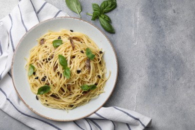 Delicious pasta with anchovies, olives and basil on light grey table, flat lay. Space for text