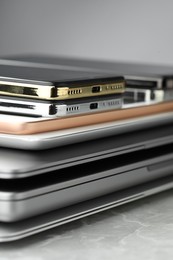 Photo of Stack of electronic devices on grey stone table, closeup