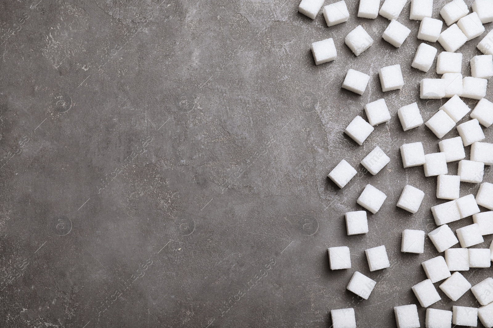 Photo of Refined sugar cubes on grey table, top view. Space for text