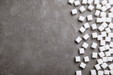 Refined sugar cubes on grey table, top view. Space for text