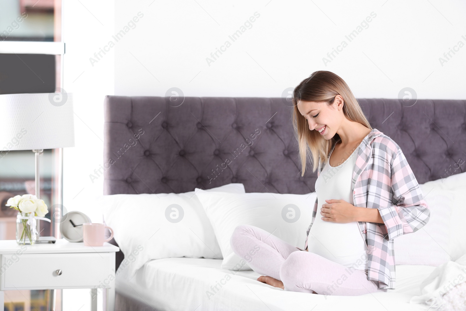 Photo of Happy pregnant woman sitting in bed at home