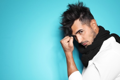 Young man with trendy hairstyle posing on color background