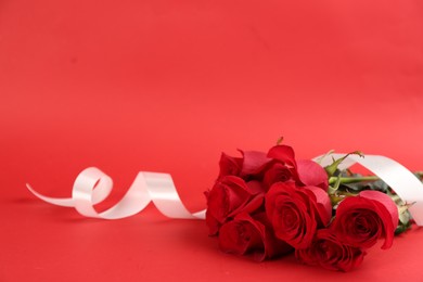 Photo of Beautiful roses with white ribbon on red background, space for text. St. Valentine's day celebration