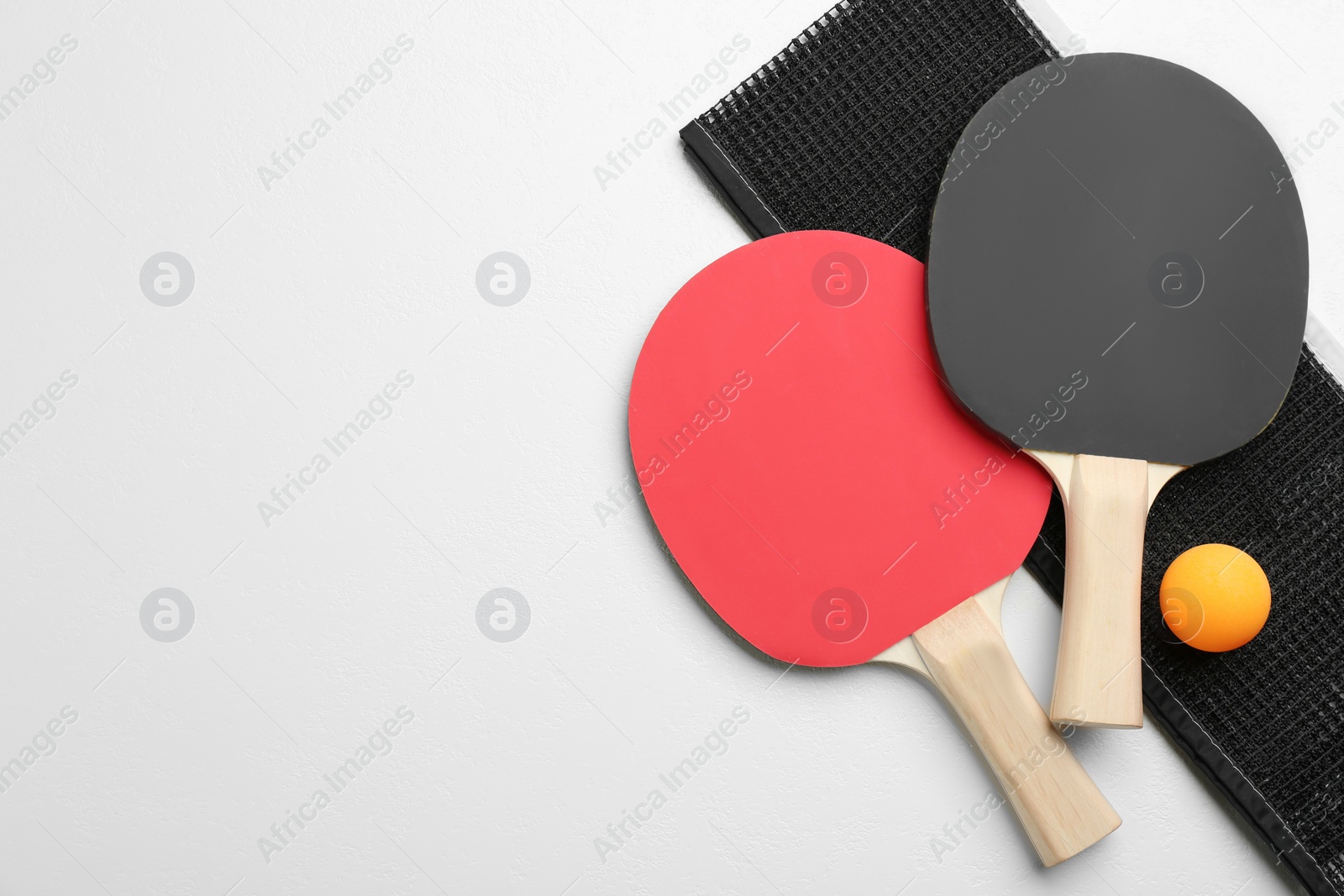 Photo of Ping pong rackets, net and ball on white table, flat lay. Space for text