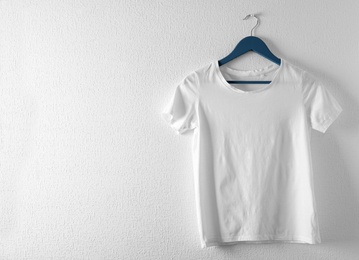 Photo of Hanger with white t-shirt on light background. Mockup for design