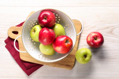 Photo of Fresh apples in colander on white wooden table, flat lay