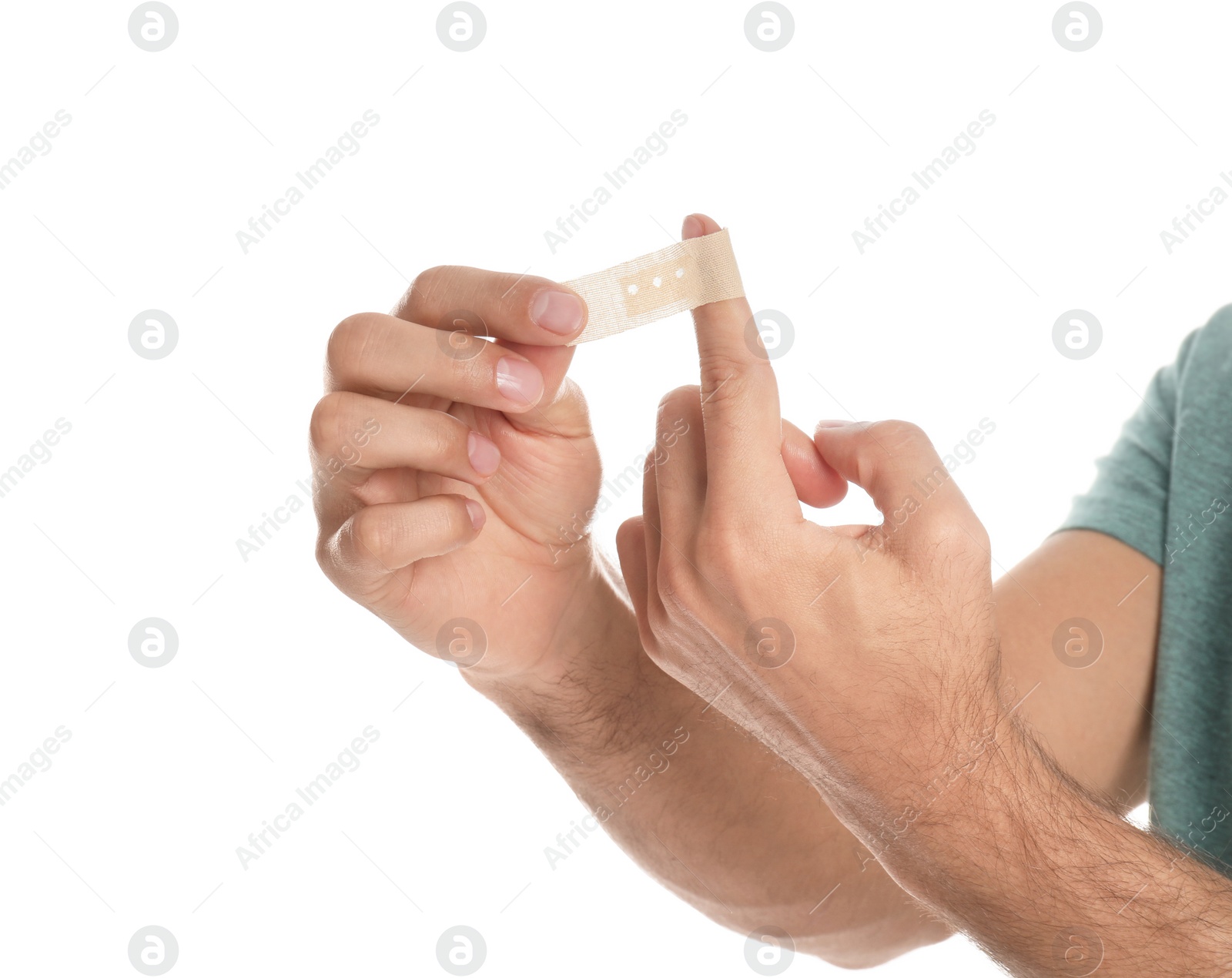 Photo of Man putting sticking plaster onto finger on white background, closeup