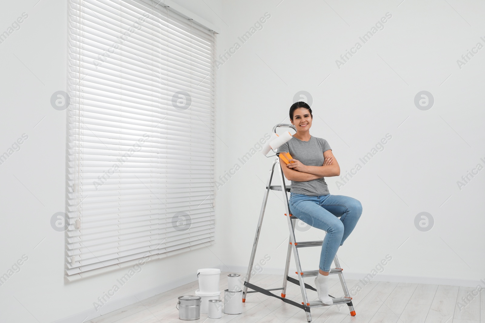 Photo of Woman sitting on metallic folding ladder indoors, space for text