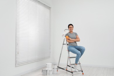 Photo of Woman sitting on metallic folding ladder indoors, space for text