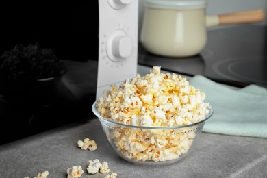 Glass bowl with tasty popcorn on table in kitchen