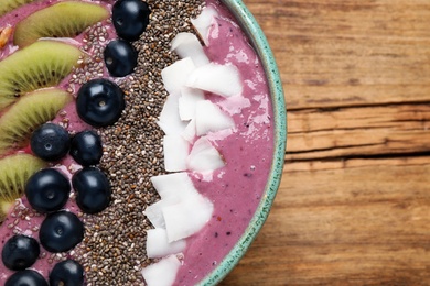 Breakfast with delicious acai smoothie and healthy ingredients in bowl on wooden table, top view. Space for text