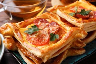 Photo of Fresh delicious puff pastry with cheese, tomatoes and parsley on plate, closeup