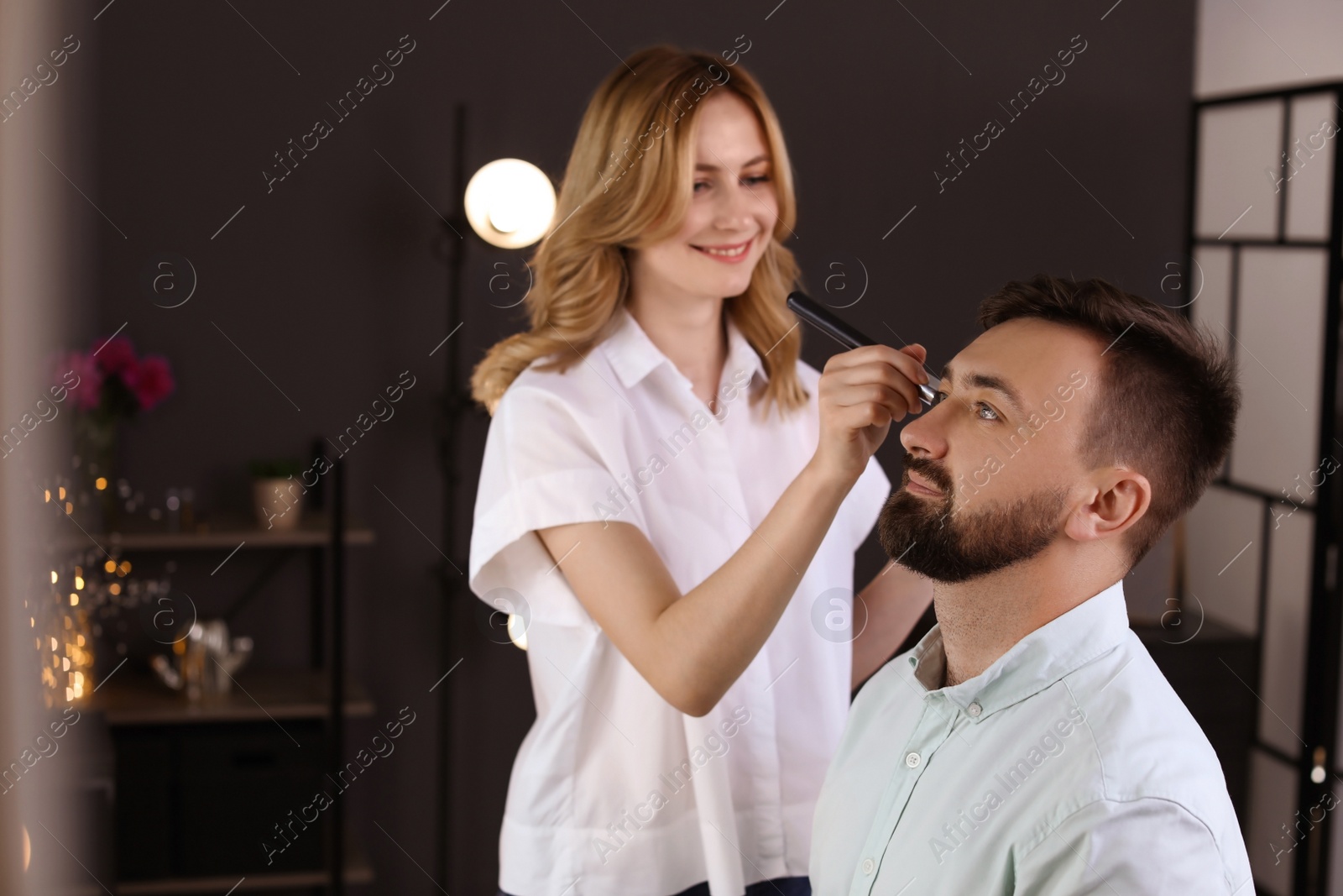 Photo of Professional makeup artist working with client in dressing room