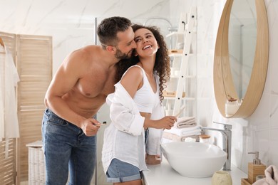 Lovely couple enjoying each other while brushing teeth in bathroom