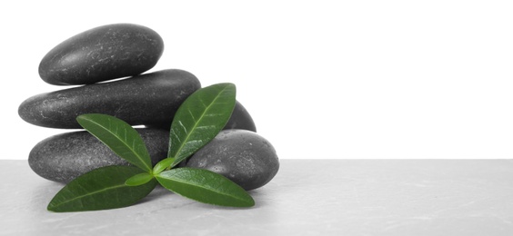 Photo of Stack of spa stones and leaves on table against white background. Space for text