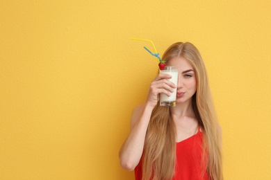 Young woman with glass of delicious milk shake on color background