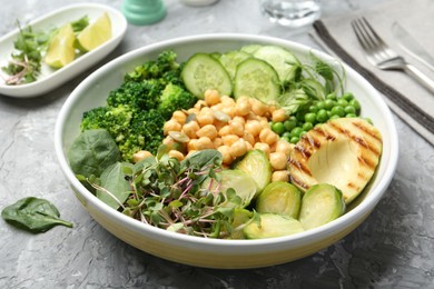 Photo of Healthy meal. Tasty vegetables and chickpeas in bowl on grey table, closeup