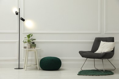 Photo of Stylish room interior with pouf, chair and houseplants. Space for text