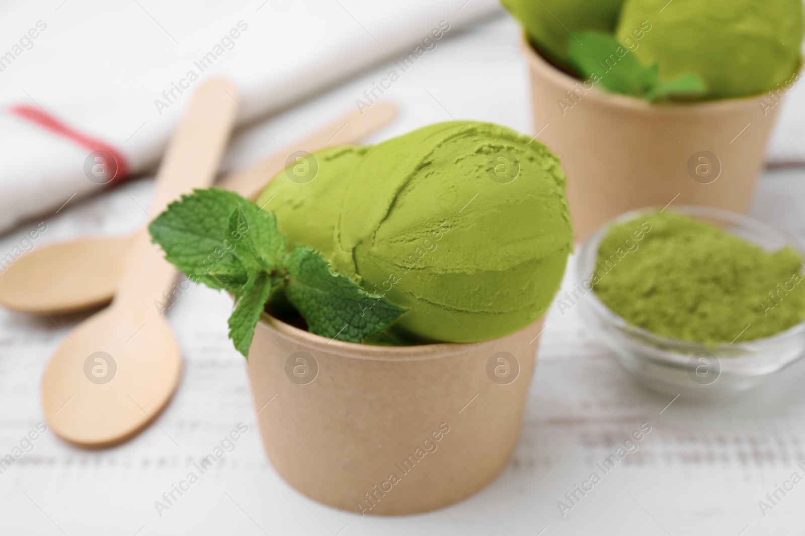 Photo of Paper cup with tasty matcha ice cream on white table, closeup
